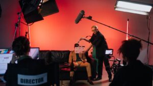 A production crew films an actor on a couch